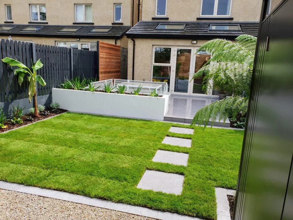 A low-maintenance small Dublin garden with large-format porcelain paving and simplified, generous planting beds requiring minimal upkeep.